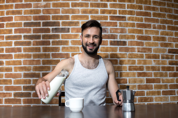 young man pouring milk at breakfast - Фото, изображение