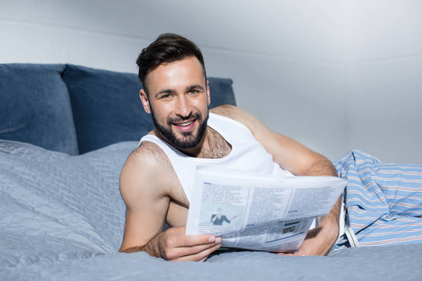 Bärtiger Mann liest Zeitung im Bett - Foto, Bild