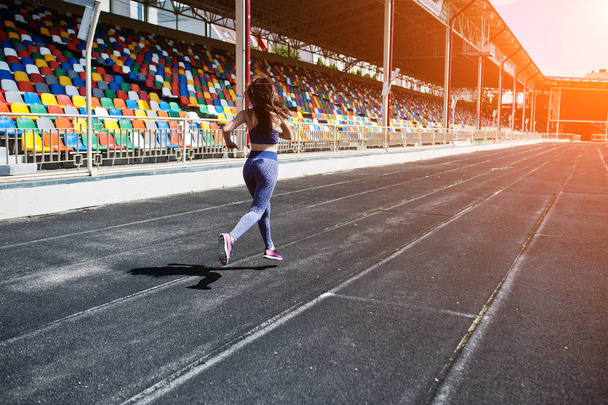 Portrait of a strong fit girl in sportswear running in the stadi - Φωτογραφία, εικόνα