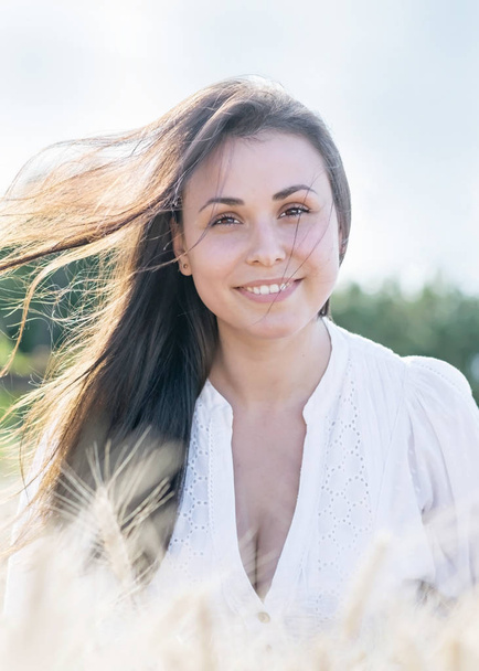 Beautiful young sexy woman with Fluttering long hair in the wind. Portrait of pretty smiling girl on nature - Фото, изображение