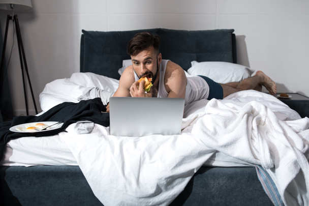 fiatal férfi használ laptop az ágyban - Fotó, kép