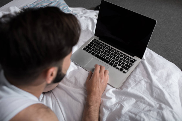 Muž přes notebook v posteli - Fotografie, Obrázek
