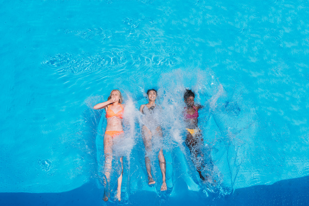 Mujeres multiétnicas nadando en la piscina
 - Foto, Imagen