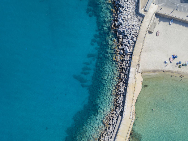 Aerial view of a pier with rocks and rocks on the sea. Pier of Pizzo Calabro, panoramic view from above. Summer sea and tourism on the Calabrian coast of Southern Italy. Calabria, Italy - 写真・画像