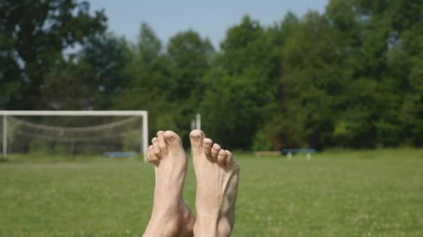 Mans feet at a trees and grass background. A happy person relaxing and having a sun bath - Footage, Video