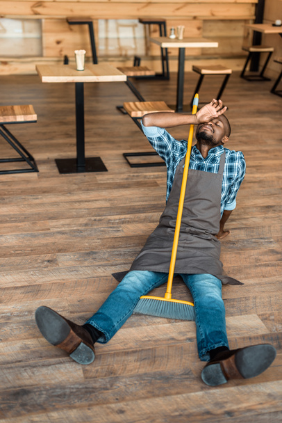 tired man on floor with broom  - Фото, изображение