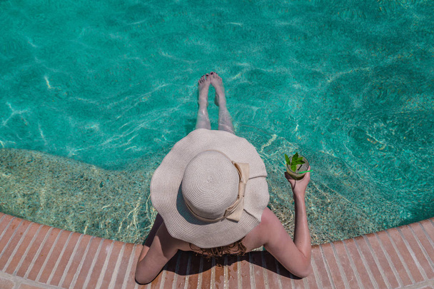 Vrouwelijke genieten in zwembad en mojito cocktail te houden. Su - Foto, afbeelding
