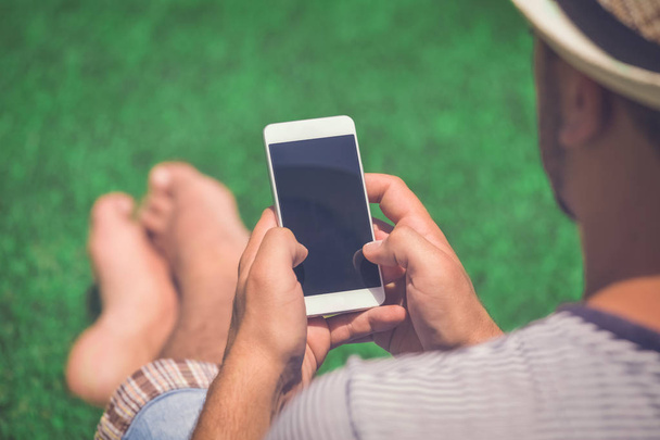 Homme assis sur l'herbe et utilisant un smartphone
 - Photo, image