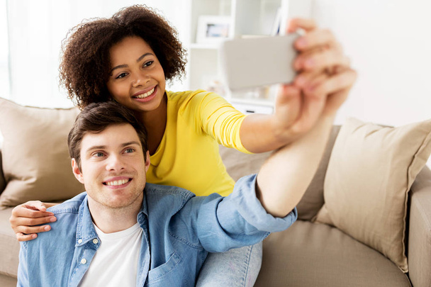 happy couple with smartphone taking selfie at home - Fotó, kép