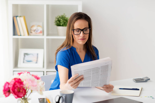 woman in glasses reading newspaper at office - Fotó, kép