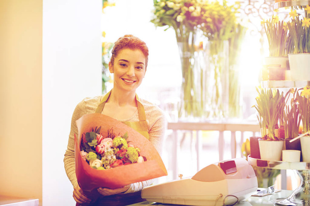smiling florist woman with bunch at flower shop - Foto, afbeelding