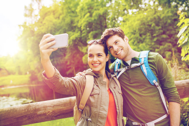 couple with backpacks taking selfie by smartphone - Фото, зображення