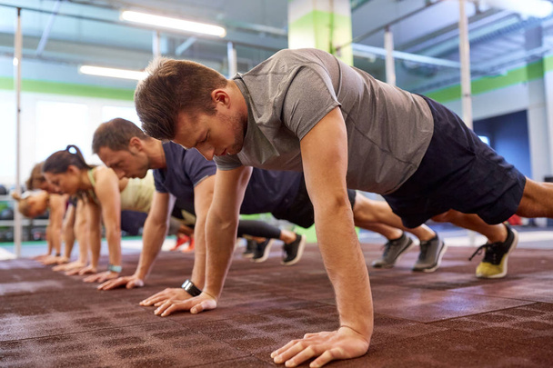 group of people doing straight arm plank in gym - Fotó, kép