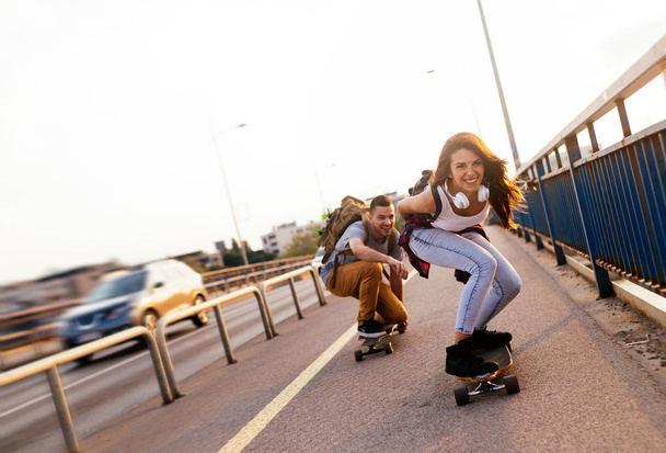Young attractive couple riding skateboards and having fun - Fotoğraf, Görsel