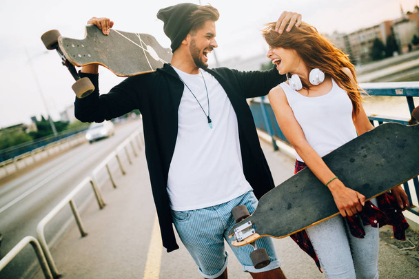 Picture of young attractive couple carrying skateboards - Zdjęcie, obraz