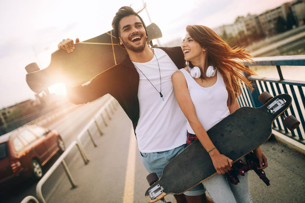 Picture of young attractive couple carrying skateboards - Foto, afbeelding