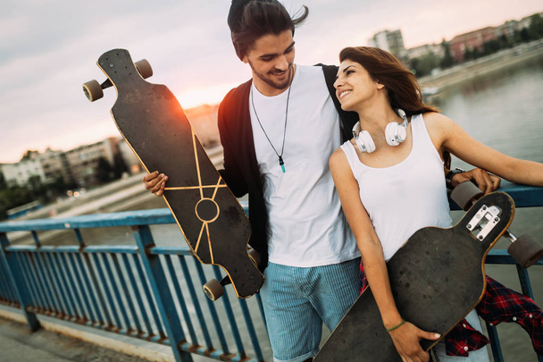 Picture of young attractive couple carrying skateboards - Foto, imagen