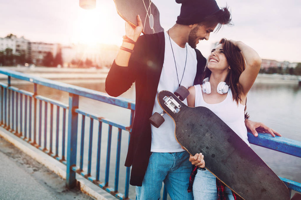 Picture of young attractive couple carrying skateboards - Photo, image