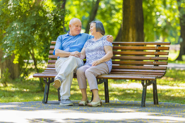 Casal de idosos relaxado conversando no banco do parque
 - Foto, Imagem
