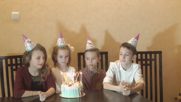 Маленькая именинница и ее друзья за праздничным столом. Дети задувают свечи на праздничном торте. празднование дня рождения детей
 - Кадры, видео