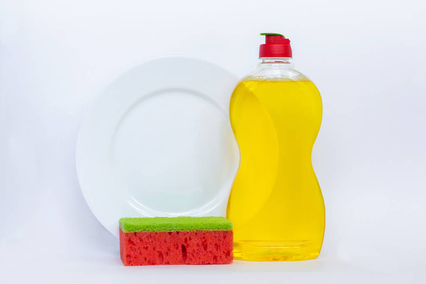 Keukengerei gele vloeistof, schone fles, schoon plaat en rood met een sponsachtige wax wassen. Watermeloen spons. Geïsoleerd op witte achtergrond. - Foto, afbeelding