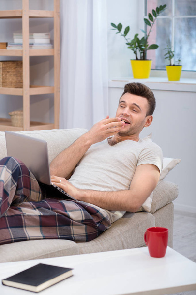 Lazy husband lying on couch and yawning. - Foto, afbeelding