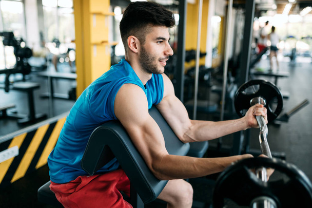 Young attractive man doing exercises in gym - Foto, afbeelding