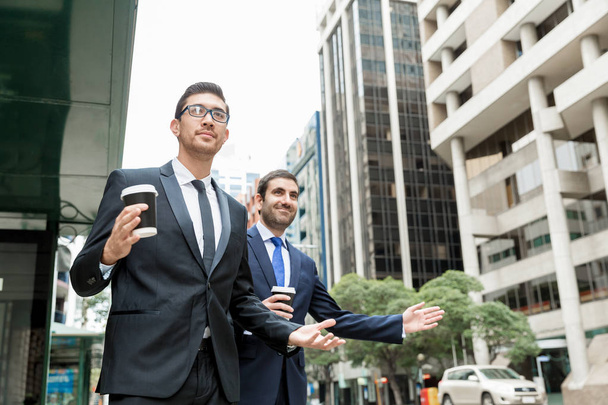 Two young businessmen hailing for a taxi - 写真・画像