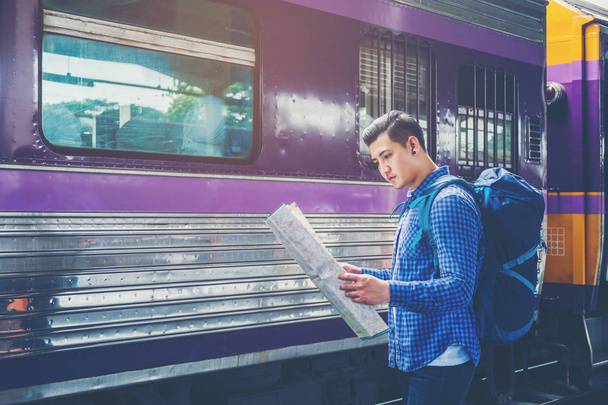 Traveler man with map and waits train on railway platform - Foto, afbeelding