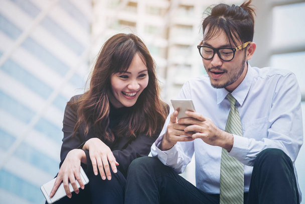 Business man and business woman enjoy using smartphone - Фото, изображение