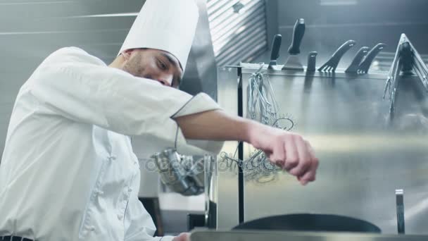 Professionele chef-kok in een commerciële keuken in een restaurant of hotel is het bereiden van voedsel op een pan. - Video