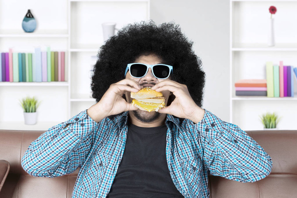 Afro hombre con gafas de sol come hamburguesa
 - Foto, Imagen