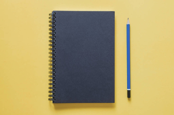 Office workplace minimal concept. Black notebook and pencil on y - Фото, зображення