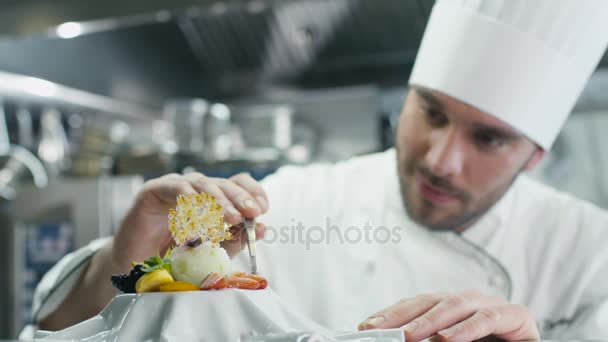 Feliz chef profesional en una cocina comercial está adornando postre de helado con fresa
. - Imágenes, Vídeo