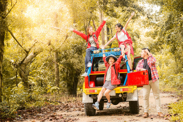 Счастливые азиатские молодые путешественники с 4WD привода автомобиль от дороги в лесу, молодая пара ищет направления на карте и еще два пользуются на 4WD привода автомобиля. Молодая смешанная раса азиатская женщина и мужчина
. - Фото, изображение