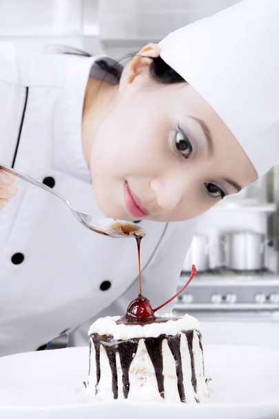 Female baker decorate a sweet cake - Фото, изображение