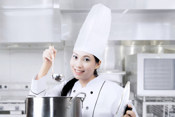 Female chef cooking with pot in kitchen - Valokuva, kuva