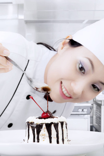 Female chef decorating a cake - Фото, изображение