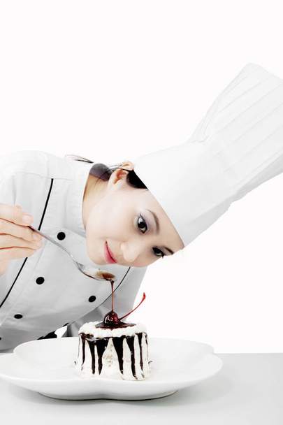 Female chef decorating a tasty cake - Foto, afbeelding