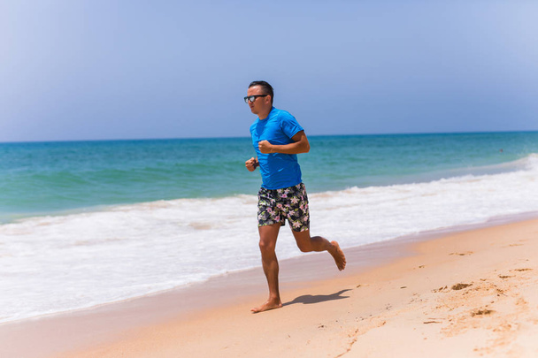 Człowiek działa na słonecznej plaży, w pobliżu oceanu - Zdjęcie, obraz