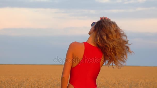 Dziewczyna w polu w czerwony strój kąpielowy. Slowmo 120fps - Materiał filmowy, wideo
