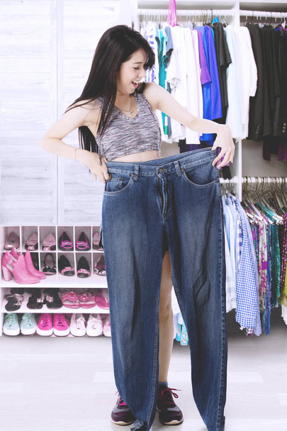 Slim woman with her old jeans - 写真・画像