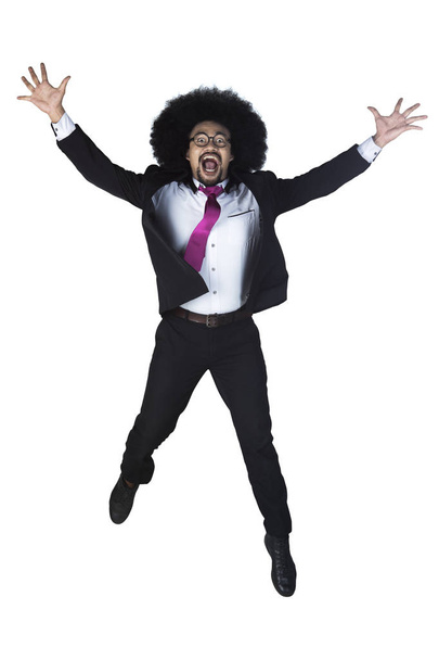 Successful businessman jumps with arms raised - 写真・画像