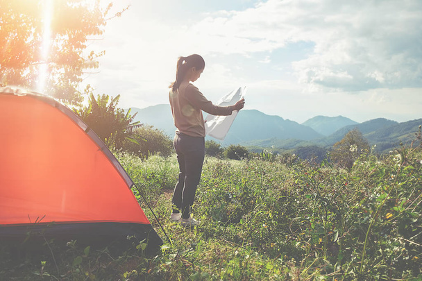 Asian hipster cute teen girl enjoying sunrise outside the tent. camping in forest - 写真・画像