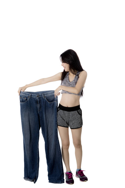 Woman with slim body holds big jeans - Foto, afbeelding
