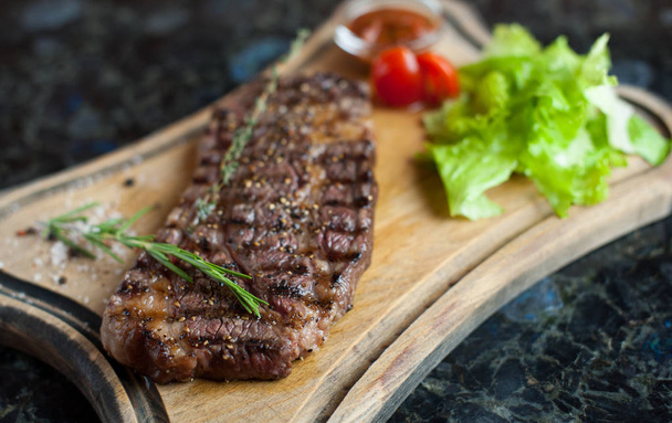 Juicy steak from marbled beef on a wooden board - 写真・画像