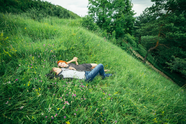 Nuori onnellinen kaunis pari mies ja nainen makaa ulkona kirkas aurinkoinen päivä vihreällä nurmikolla
 - Valokuva, kuva