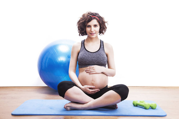 Молодая беременная женщина упражняется на коврике
 - Фото, изображение