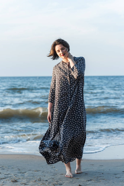 Szép lány egy ruhában pózol a tenger közelében - Fotó, kép