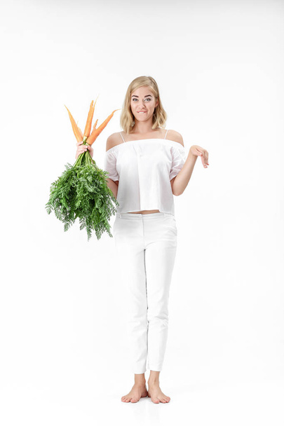 Beautiful blond woman showing rabbit and holding fresh carrot with green leaves on white background. Health and Diet - Photo, Image